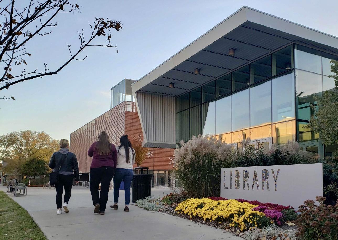 Lawrence residents walk up the sidewalk toward the entrance of the Lawrence public library (copy)